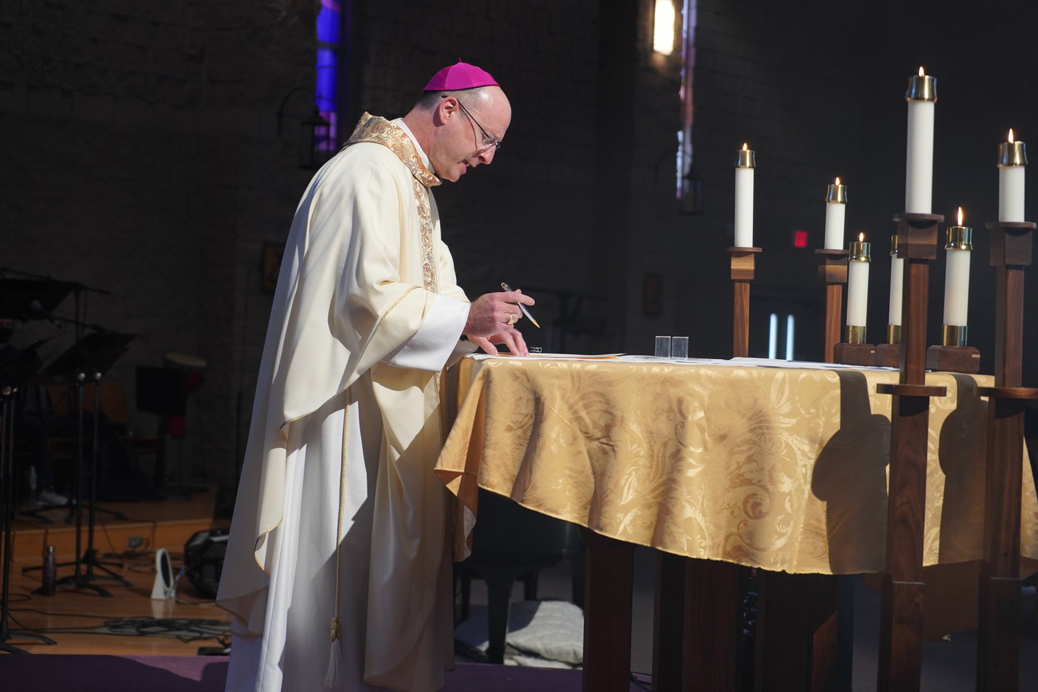 Bishop W. Shawn McKnight signs his first pastoral letter as bishop of Jefferson City, promulgating the new pastoral plan for the Jefferson City diocese, while celebrating Mass with college students Feb. 6 in the St. Thomas More Newman Center Chapel in Columbia. — Photo by Jay Nies